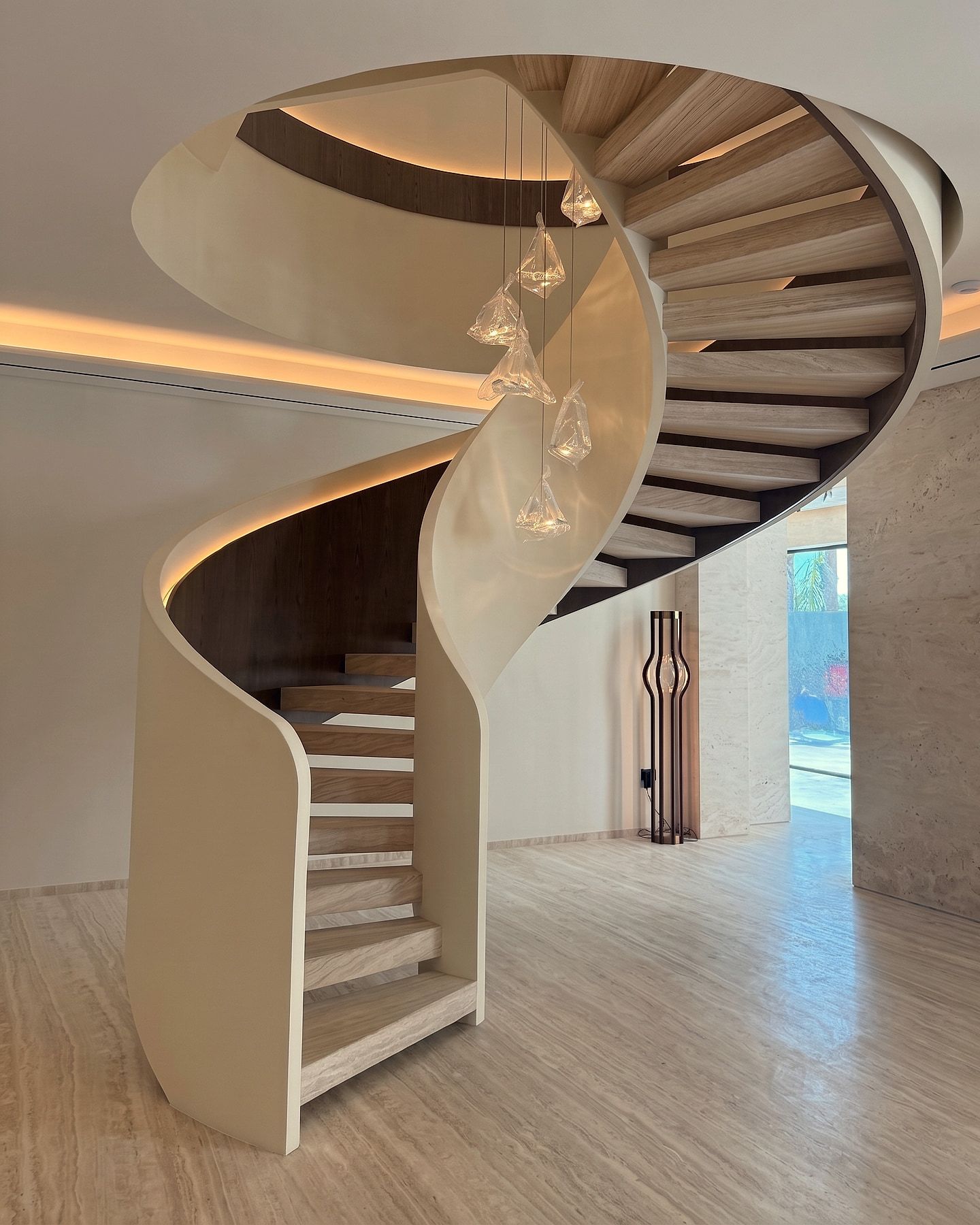 Seen from the landing — winder treads fanning around the newel, with a hand-blown glass cluster hung down the centre.