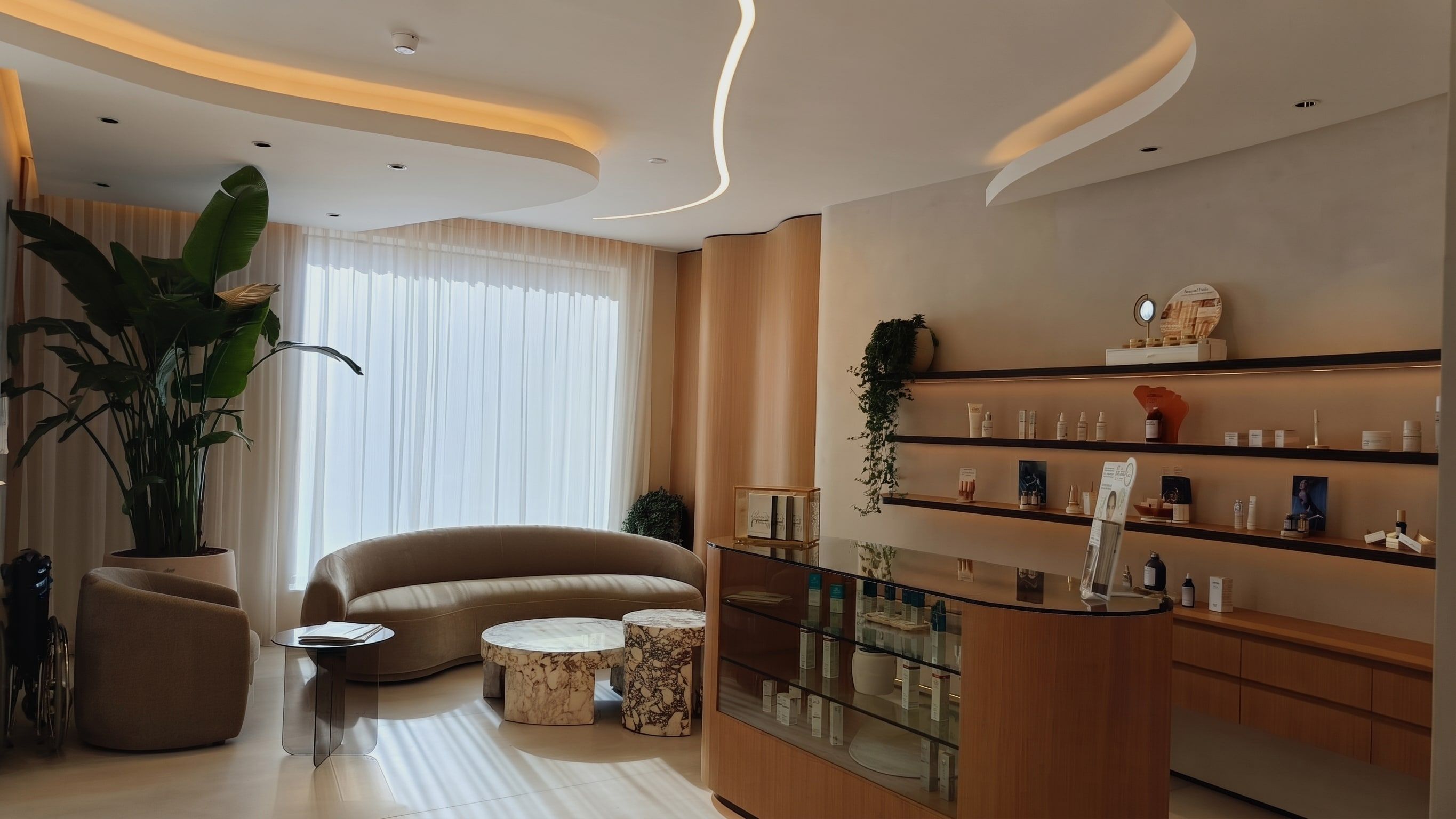 Fluted oak panelling, a curved display counter and backlit shelving under a sculpted cove ceiling.