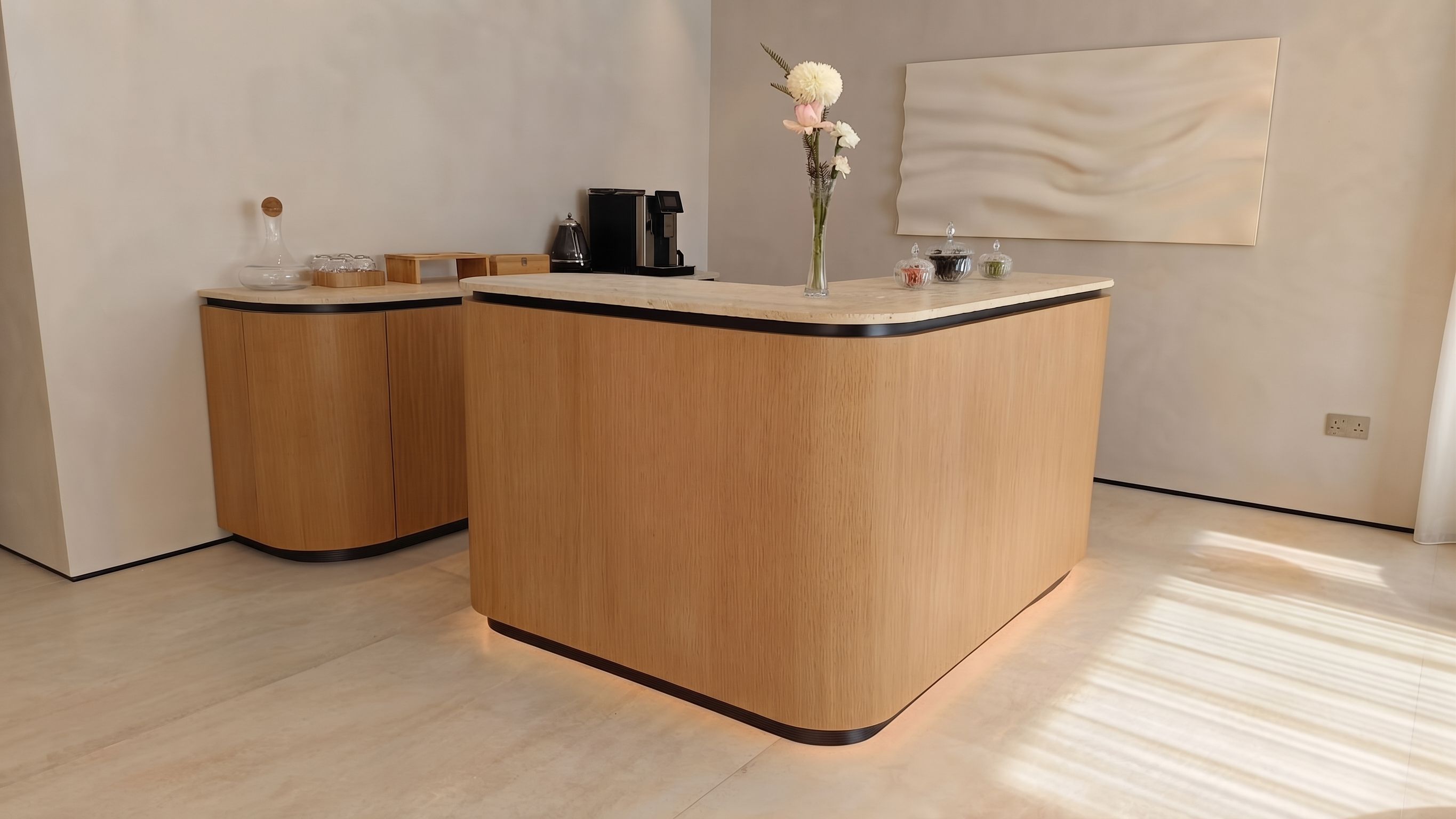 Curved oak joinery with a travertine top, black reveal detail and concealed skirting light.