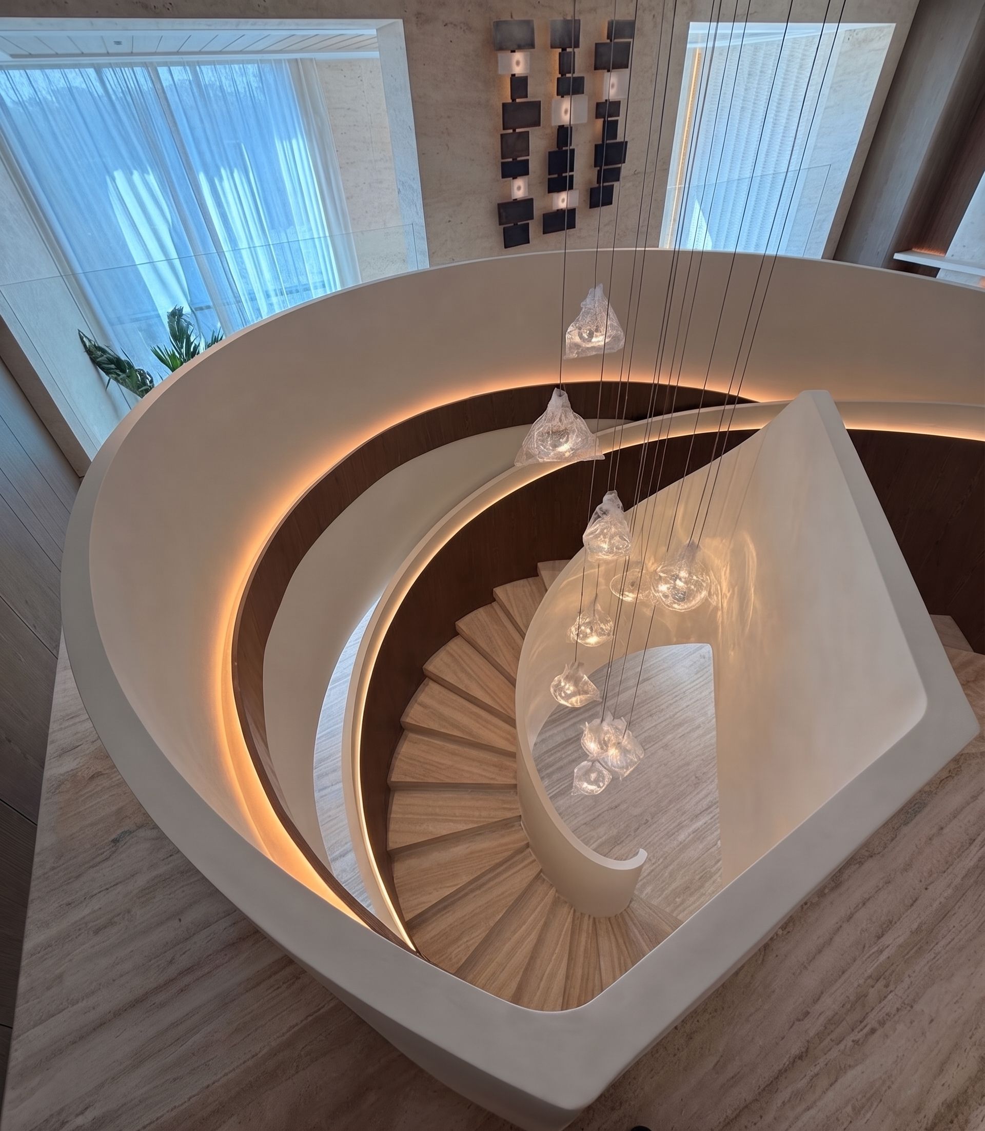 Seen from the landing — winder treads fanning around the newel, with a hand-blown glass cluster hung down the centre.