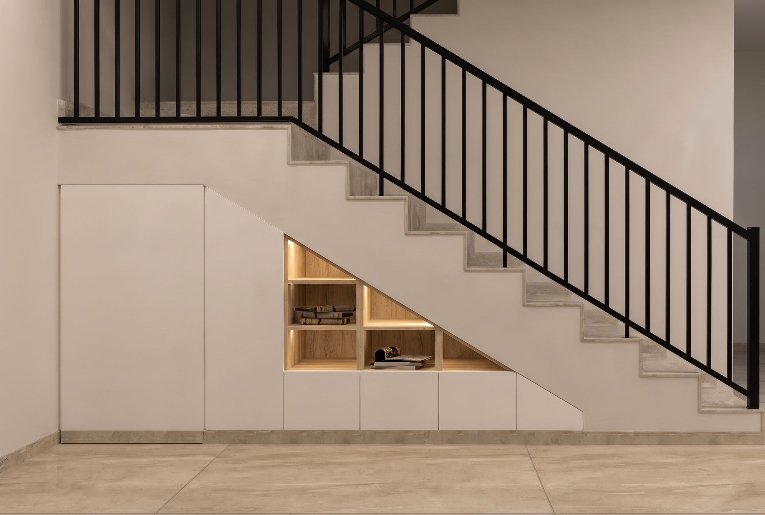 3D visual — the space under a steel-balustraded flight taken up by flush cupboards and a lit display cube.