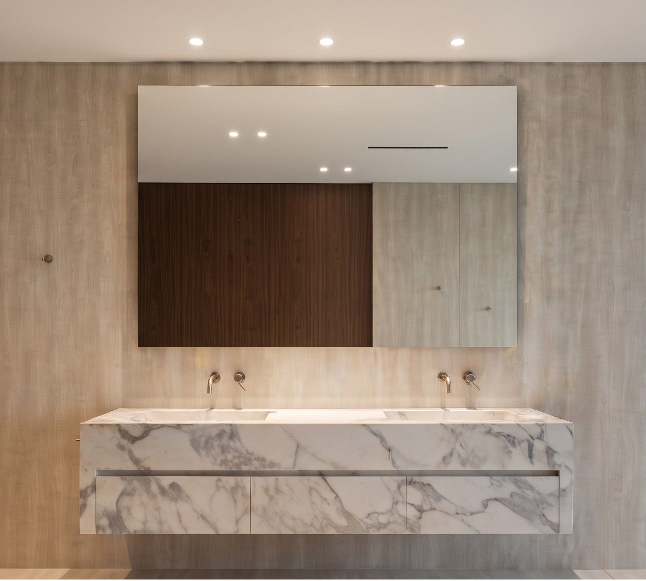 Wall-mounted brassware, a full-width mirror and a marble counter with concealed drawer runners.